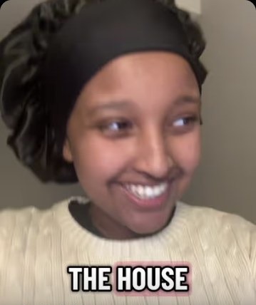 Isra Yasin delivering a joke straight to camera in low light
